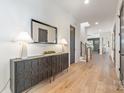 A stylish hallway featuring hardwood floors, modern decor, a decorative cabinet, and a large mirror at 3945 Plainview Rd, Charlotte, NC 28208