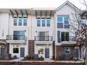 An exterior view shows the townhome with brick and white siding, a balcony and black railings at 1409 Collier Walk Aly # Csw0104, Charlotte, NC 28205