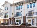 Modern townhome with white siding, brick accents, a balcony, and a well-manicured lawn at 1411 Collier Walk Aly # Csw0105, Charlotte, NC 28205