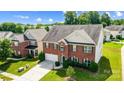 Aerial view of a brick two-story home with a two-car garage and green lawn at 14447 Waterlyn Dr, Charlotte, NC 28278