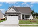 Inviting single-story home showcasing stone accents, a two-car garage, and a lush green lawn at 126 Brixham Loop, Troutman, NC 28166