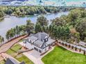 Stunning aerial view of a modern farmhouse situated on a waterfront property, surrounded by lush trees at 110 Emmaline Ct, Troutman, NC 28166