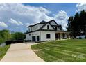 Side view of a modern farmhouse with a spacious driveway and well-maintained lawn leading to the garage at 110 Emmaline Ct, Troutman, NC 28166