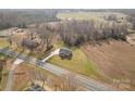 An aerial perspective of a gray home with a long driveway on a spacious lot, surrounded by fields and trees at 8255 W Nc 10 Hwy, Vale, NC 28168