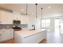 Elegant kitchen features white cabinets, quartz countertops, stainless steel appliances and oversized island with pendant lights at 133 Armstrong Rd, Belmont, NC 28012