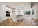 Modern, open-concept kitchen with white cabinets, island, stainless steel appliances and hardwood floors at 104 Brooke Forest Ct, Mooresville, NC 28115