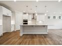 Bright, open-concept kitchen with island, pendant lighting, stainless steel appliances, and hardwood floors at 104 Brooke Forest Ct, Mooresville, NC 28115