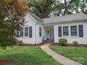 White house with black shutters, brick walkway, and lush green lawn at 705 Neil St, Gastonia, NC 28052