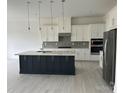 Modern kitchen featuring a large island, stainless steel appliances, and sleek white cabinetry at 5209 Mint Harbor Way # 0352, Charlotte, NC 28269