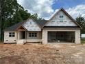 Under-construction brick home with a spacious attached garage, black roof, and covered front porch, set in a wooded area at 1500 Crowders Creek Rd, Gastonia, NC 28052