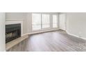 This living room features a fireplace, large windows, hardwood floors and a white front door at 1600 Sharon W Rd # 11, Charlotte, NC 28210