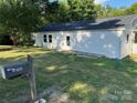 Exterior view of a white home with mature landscaping, lawn, and dark roof at 702 N 9Th St, Bessemer City, NC 28016