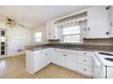 Bright kitchen featuring white cabinets, a double sink, tile countertops, and a view to the back yard at 2001 Mcdonald Dr, Charlotte, NC 28216