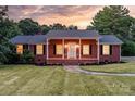 Brick ranch house with covered porch, lit at dusk, landscaped yard at 2909 Eastway Dr, Statesville, NC 28625