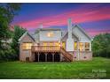 Backyard view featuring a spacious deck, lush green lawn, and the home's classic brick exterior at 160 Northington Woods Dr, Mooresville, NC 28117