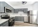 Modern kitchen features stainless steel appliances, grey cabinets, and stylish backsplash and light counter tops at 12229 Savannah Garden Dr, Charlotte, NC 28273