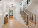 Bright entryway with wood floors, staircase with black railings, and modern light fixture at 626 Concord Rd, Davidson, NC 28036