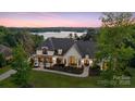 Stunning lakeside home with a modern exterior, manicured lawn, and beautiful landscaping at sunset at 18304 Rosapenny Rd, Charlotte, NC 28278
