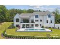 Back exterior view featuring a refreshing pool, multiple patios, and meticulous landscaping at 18304 Rosapenny Rd, Charlotte, NC 28278