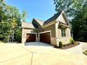 Spacious three-car garage with stone accents and a concrete driveway, surrounded by lush greenery at 859 Tamary Way # 34, Landis, NC 28088