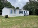 A single-story home featuring white siding, blue shutters, and a covered front porch, with a verdant lawn at 6261 Burnhurst Ln, Denver, NC 28037