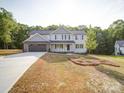 Well-manicured front yard leading to a charming two-story home with a two-car garage and blue siding at 1133 Heather Oak Ln, Oakboro, NC 28129