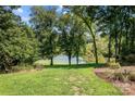 Peaceful backyard view overlooking a pond, lush green grass, and mature trees at 721 Orphanage Rd, Concord, NC 28027