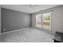 Serene bedroom with neutral paint, plush carpeting, and a large window for ample natural light at 9341 Lenox Pointe Dr, Charlotte, NC 28273