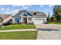 Inviting home exterior featuring manicured lawn, stone accents and a two-car garage at 16004 Deer River Rd, Charlotte, NC 28278
