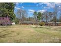 A brick home with a large lawn and mature trees under a blue sky at 1206 Mineral Springs Rd, Charlotte, NC 28262