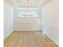 Elegant dining room featuring tray ceilings, a modern chandelier, and classic wainscoting detail at 10108 Whitaker Pointe Dr, Huntersville, NC 28078