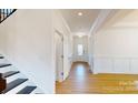 Inviting hallway with hardwood floors and white wainscoting leading to a glass-paneled front door at 10108 Whitaker Pointe Dr, Huntersville, NC 28078