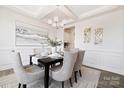 The dining room has a tray ceiling, white wainscotting, and an elegant chandelier at 121 Saidin Ln, Troutman, NC 28166