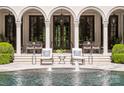 Covered terrace with seating area overlooking a pool with fountains and lush greenery at 423 Oakmont Ln, Waxhaw, NC 28173