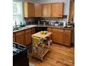Functional kitchen boasts oak cabinets, dark countertops, and hardwood floors, complete with an island at 3329 Draper Ave, Charlotte, NC 28205
