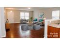 Inviting living room featuring hardwood floors, a comfortable gray sofa, and ample natural light from large windows at 1327 Phil Oneil Dr, Charlotte, NC 28215