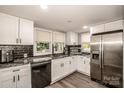 Modern kitchen with white cabinets, stainless steel appliances, and black countertops at 60 Hunter Bridge Rd, Stony Point, NC 28678