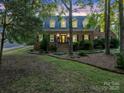 Charming two-story brick home with dormer windows, black shutters, and mature trees at dusk at 8503 Foxbridge Dr # 16, Matthews, NC 28104