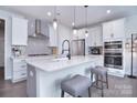 Modern kitchen features white cabinets, quartz countertops, and stainless steel appliances at 5911 Mantle Way, Kannapolis, NC 28081