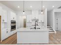 Modern kitchen featuring white cabinets, island, stainless steel appliances, and light wood floors at 1190 Lost Cove Rd, Indian Land, SC 29707