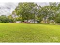 Expansive green lawn surrounds a cozy cottage-style home with mature trees, offering a serene setting at 422 Lee Ave, Wadesboro, NC 28170