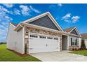 Garage exterior featuring a white garage door, stone accents, and well-maintained landscaping at 180 Wembury Ln, Troutman, NC 28166