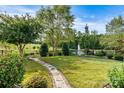 Expansive backyard featuring lush lawn, decorative stone path, mature trees, and serene pond with fountain at 8121 Festival Way, Charlotte, NC 28215