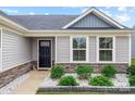Inviting entryway with stone veneer, green shrubbery, and a black front door at 4280 Stream Dale Cir, Concord, NC 28027