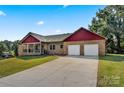 Two-car garage and a nicely landscaped yard with red siding at 5441 Suttlemyre Ln, Hickory, NC 28601