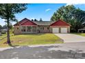 Ranch style home with red siding, two-car garage, and grassy yard at 5441 Suttlemyre Ln, Hickory, NC 28601