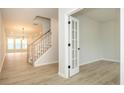 Hallway with light wood floors, staircase, and French doors leading to an office at 10507 Boudreaux St, Huntersville, NC 28078
