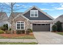 Charming single-Gathering home showcasing stone accents, gray siding, a well-maintained lawn, and an attached garage at 16115 Lakeside Loop Ln, Cornelius, NC 28031