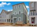 Three-story townhome with light green siding and brick accents at 207 Davidson Gateway Dr, Davidson, NC 28036