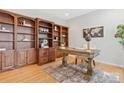 A home office featuring built-in bookshelves and a classic wooden desk on hardwood floors at 3015 Duclair Ln, Fort Mill, SC 29707